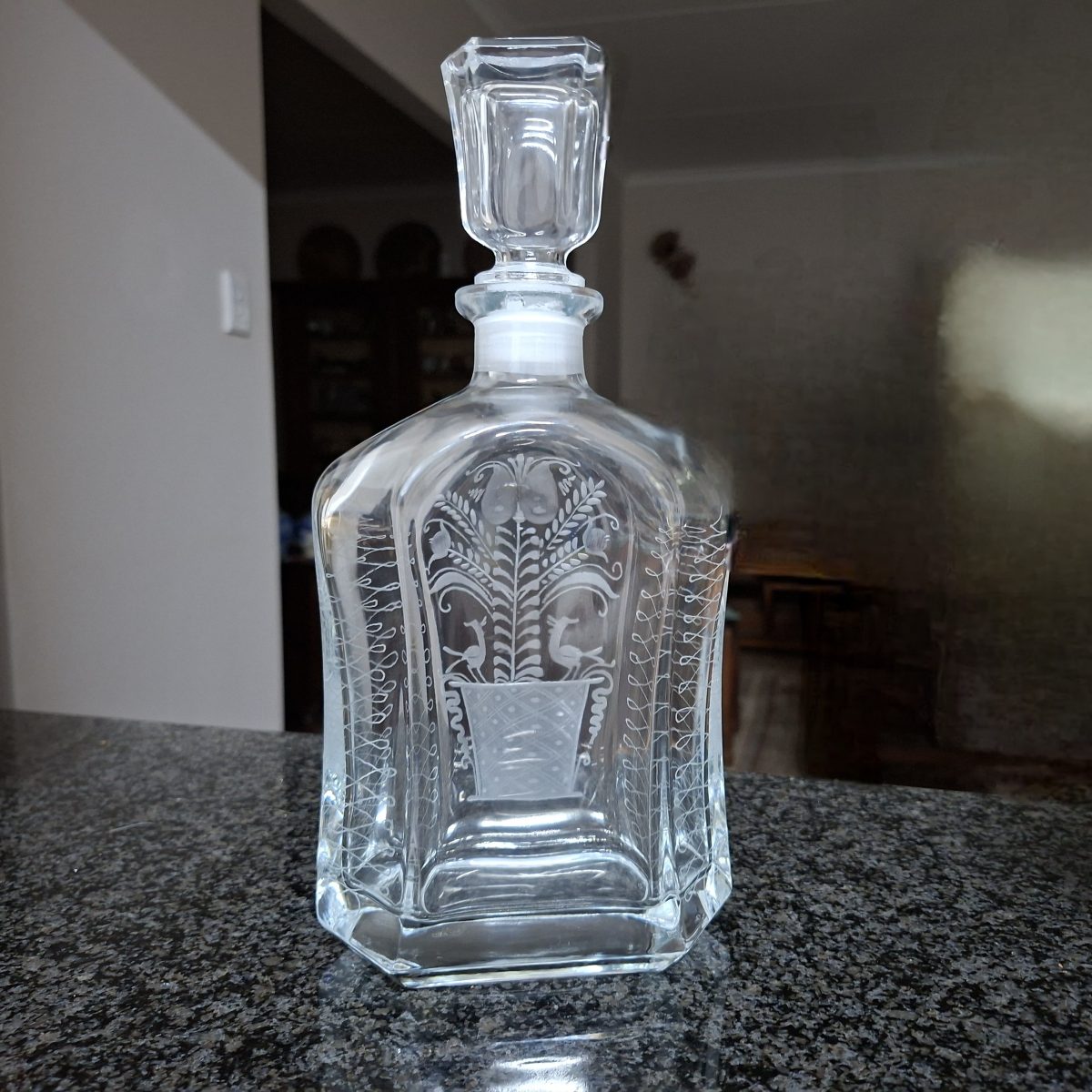 Etched heavy glass decanter with birds and foliage in a vase.