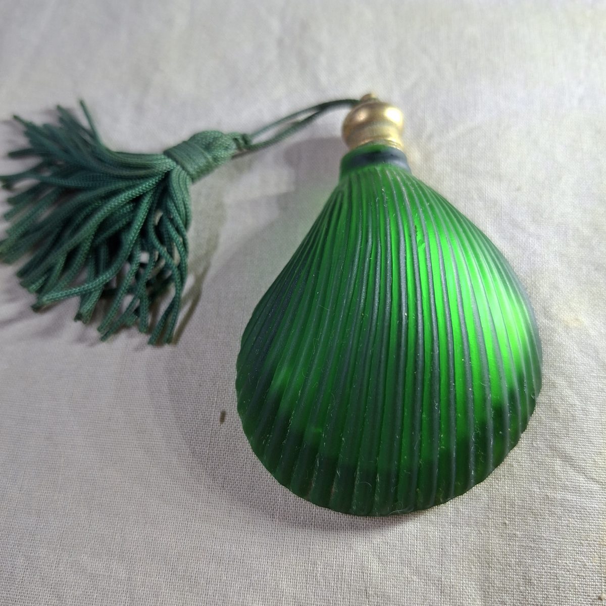Green glass perfume bottle - shell shaped flat on one side.  7.5 x 5 cms